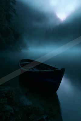 A wooden rowboat rests on the misty shore of a calm lake surrounded by dense fog and dark forested mountains at night.