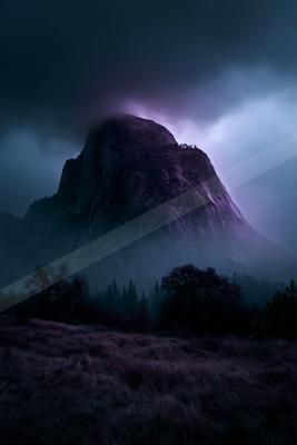 A massive rocky mountain peak rises through thick fog and dark storm clouds illuminated with purple and blue light, with a foreground of grassy meadow and silho