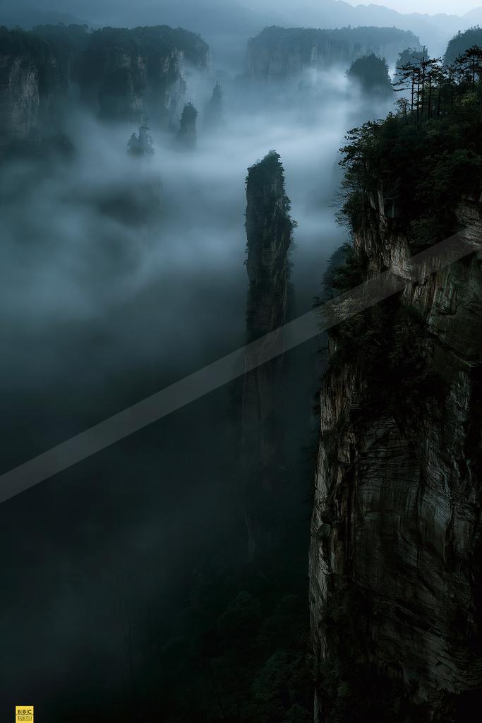 A dramatic landscape of mountains, valley, fog.