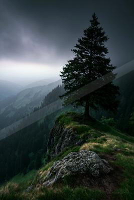 A black-toned moody photograph of alp, cliff, valley.