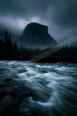 A dramatic long exposure water scene of river, storm, mountains.