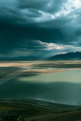 A blue hour long exposure sky scene of clouds, lake, storm.