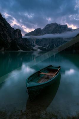 A black-toned moody photograph of canoe, lakeside, paddle.
