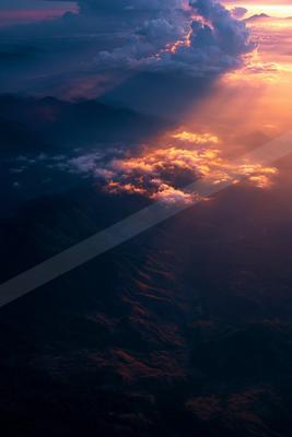 A moody landscape of mountains, sunset, clouds.