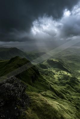 A dramatic landscape of mountains, valley, storm.