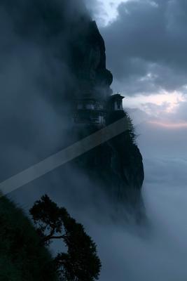 A traditional multi-tiered monastery built on the edge of a steep rocky cliff, surrounded by thick swirling clouds and mist under a dramatic twilight sky, with 