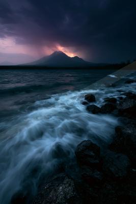 A blue hour long exposure water scene of ocean, storm, rocks.