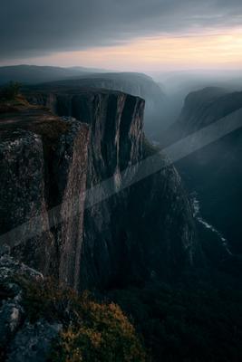 A dramatic landscape of valley, mountains, waterfall.