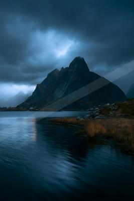 A blue hour long exposure landscape of mountains, lake, storm.