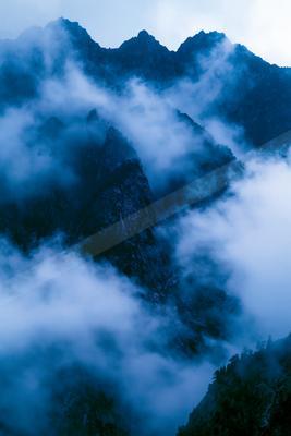 A bright sky scene of clouds, mountains, lake.