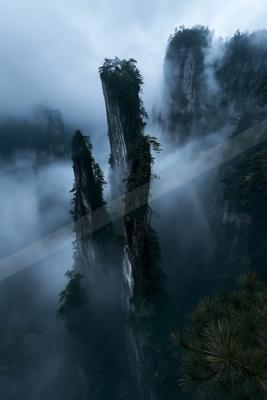 Towering mountain peaks shrouded in dense mist and fog, creating a mystical atmosphere.