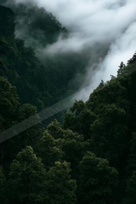 A black-toned moody photograph of valley, cliff, lakeside.