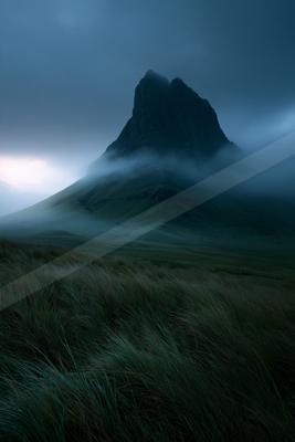 A black-toned moody photograph of volcano, promontory, valley.
