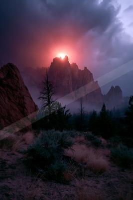 A dramatic landscape of mountains, sunrise, fog.