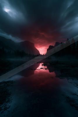 A dramatic landscape at night features a vibrant red and dark cloudy sky above silhouetted mountains and pine trees, with the intense colors reflected in a fore