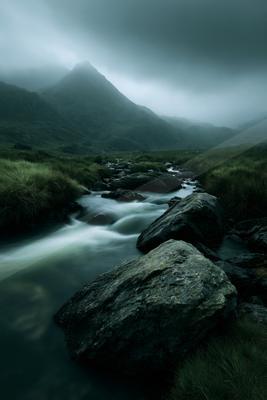 A serene long exposure water scene of river, mountains, fog.