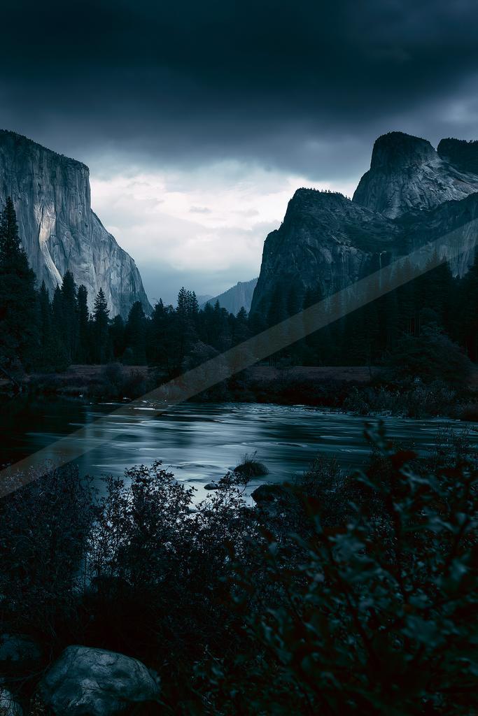 A blue hour landscape of valley, mountains, river.