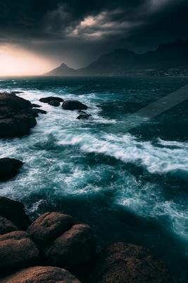 A green-toned moody photograph of seashore, promontory, cliff.