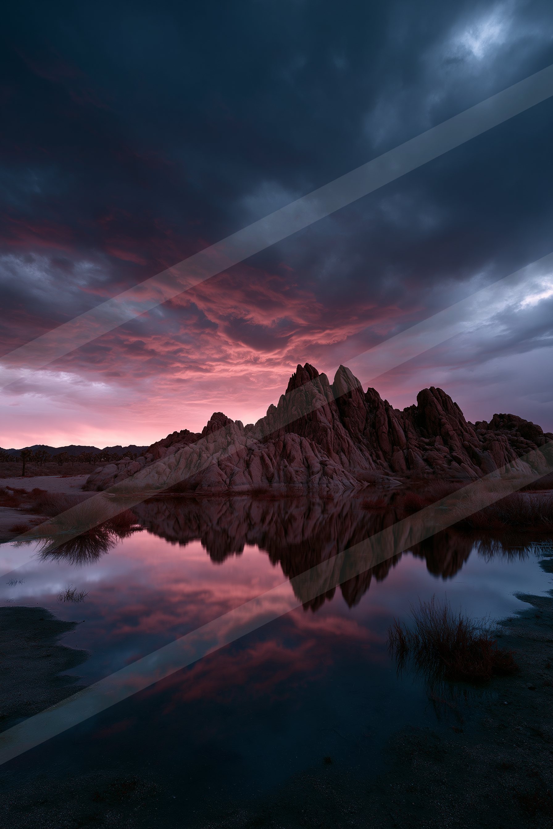 A breathtaking sunset scene featuring rugged mountains reflected perfectly in a calm body of water.