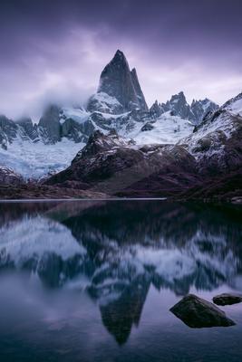 A dramatic landscape of mountains, lake, reflection.