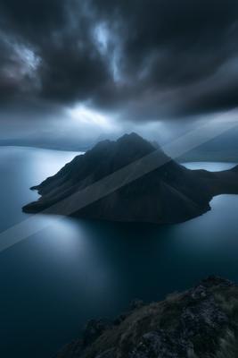 A night long exposure sky scene of storm, mountains, lake.