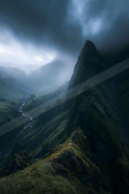 A dramatic landscape of mountains, storm, valley.