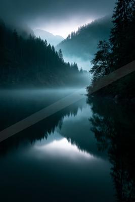 A black-toned moody photograph of lakeside, valley, boathouse.