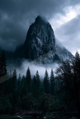 A dramatic landscape of mountains, fog.