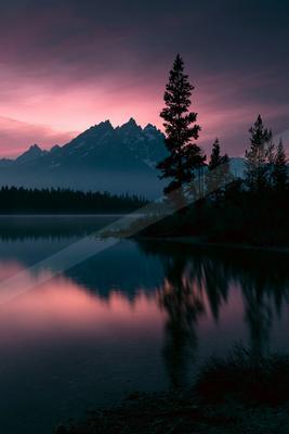A serene landscape of mountains, lake, sunset.