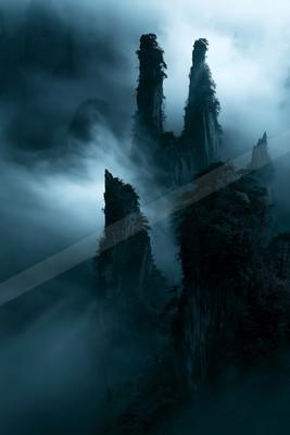 A dramatic landscape of mountains, fog.