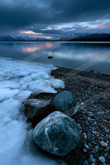A blue hour long exposure water scene of a lake, rocks.