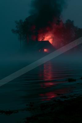 A wooden house engulfed in flames with thick smoke rising, its fiery glow reflecting on the calm surface of a misty lake at night.