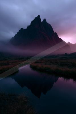 A moody landscape of mountains, lake, valley.