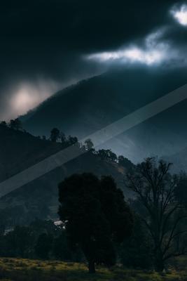 A black-toned moody photograph of valley, cliff, volcano.