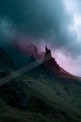 A dramatic mountain landscape at twilight, featuring towering rock formations silhouetted against a moody sky with swirling clouds in shades of blue and pink.