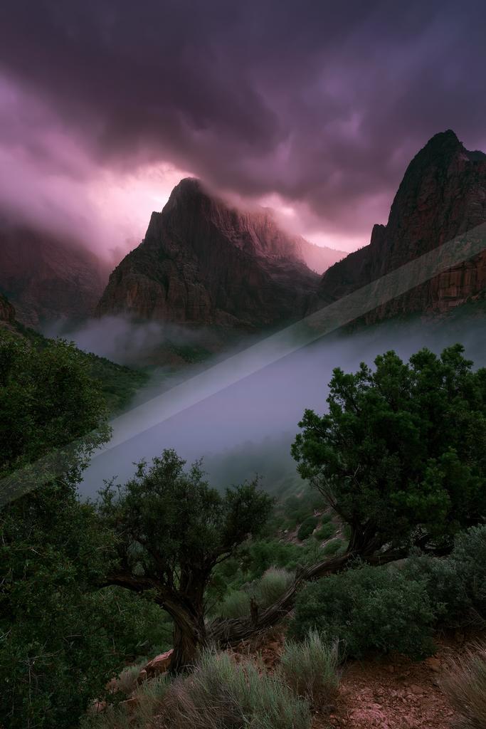 A serene landscape of mountains, valley, storm.