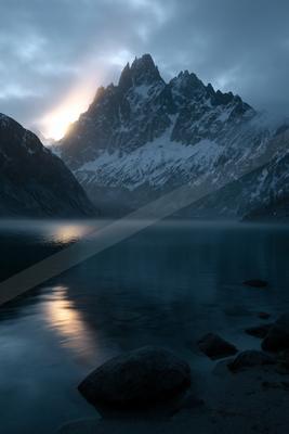 A black-toned moody photograph of alp, valley, lakeside.