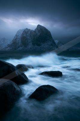 A blue hour long exposure water scene of a coastline, fog.