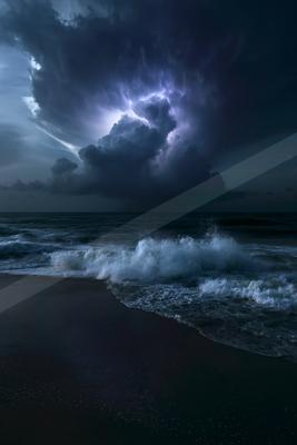Powerful lightning bolt strikes from dark storm clouds over a turbulent ocean with large white waves crashing onto a dark sandy beach at night.