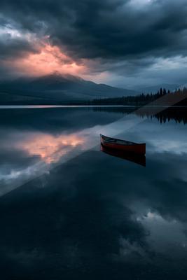 A brown-toned moody photograph of canoe, paddle, boathouse.