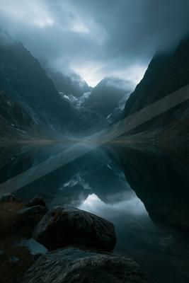 A dramatic long exposure water scene of lake, mountains, reflection.