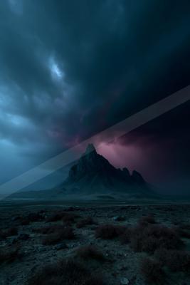 A rugged mountain peak is dramatically lit by lightning under a stormy night sky, with sparse desert vegetation in the foreground.