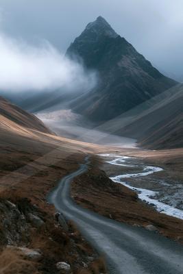 A bright landscape of mountains, valley, road.