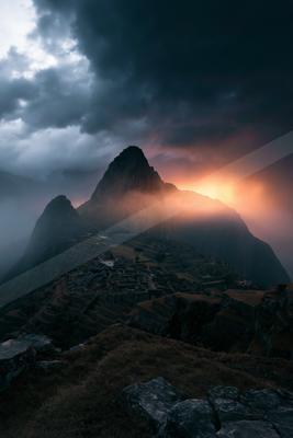 A dramatic landscape of mountains, storm, fog.