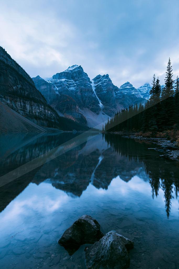 A serene water scene of lake, mountains, reflection.