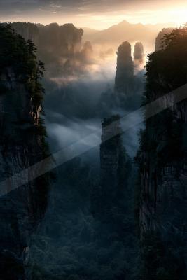A dramatic landscape of valley, mountains, fog.