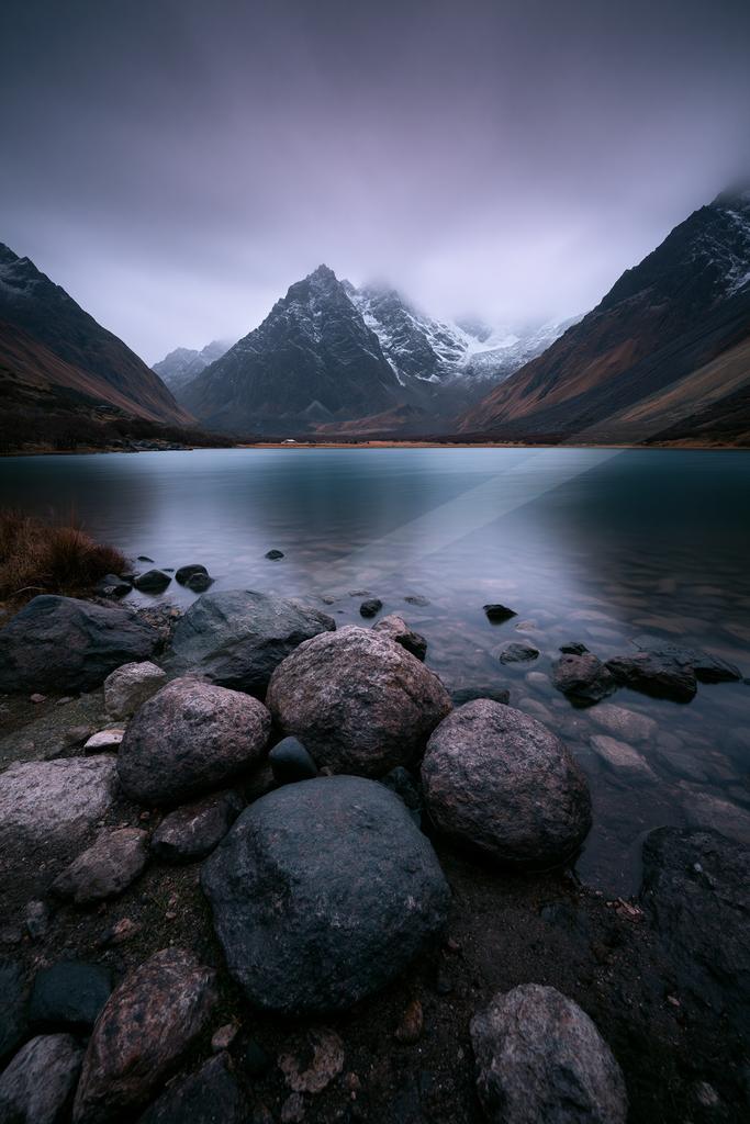 A moody landscape of mountains, lake.