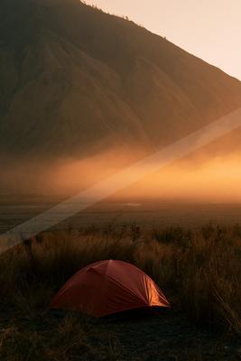 A serene landscape of mountains, sunrise, fog.