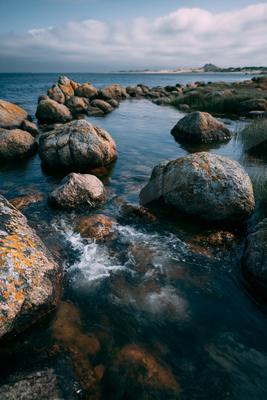 A serene long exposure water scene of ocean, river, beach.