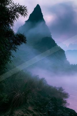 A moody landscape of mountains, valley, forest.